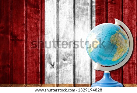 Globe with a world map on a wooden background with the image of the flag of Peru. The concept of travel and leisure abroad.