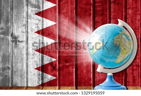 Globe with a world map on a wooden background with the image of the flag of Bahrain. The concept of travel and leisure abroad.