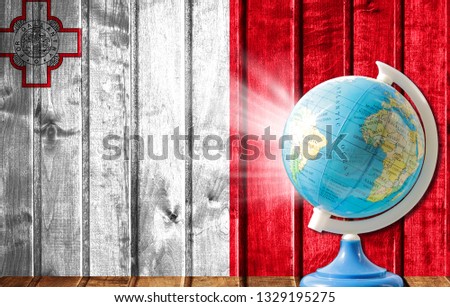 Globe with a world map on a wooden background with the image of the flag of malta. The concept of travel and leisure abroad.