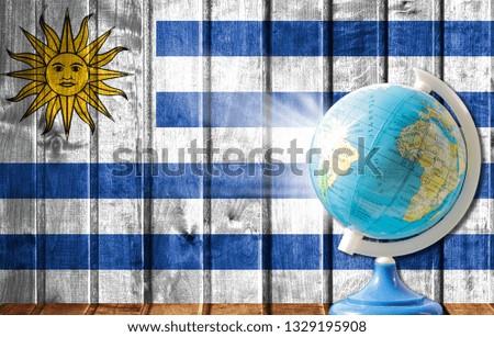 Globe with a world map on a wooden background with the image of the flag of Uruguay. The concept of travel and leisure abroad.