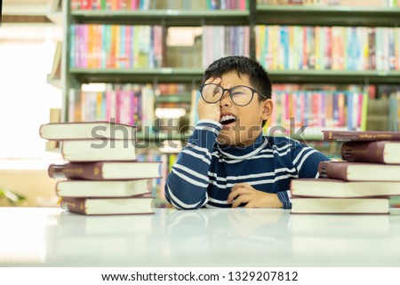  asia boy wearing glasses student with many books chained to the desk and preparing for exams.Education Knowledge concept
