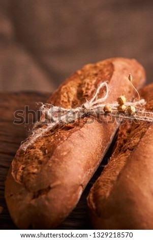 Two Fresh baguettes on dark wooden table. Selective focus