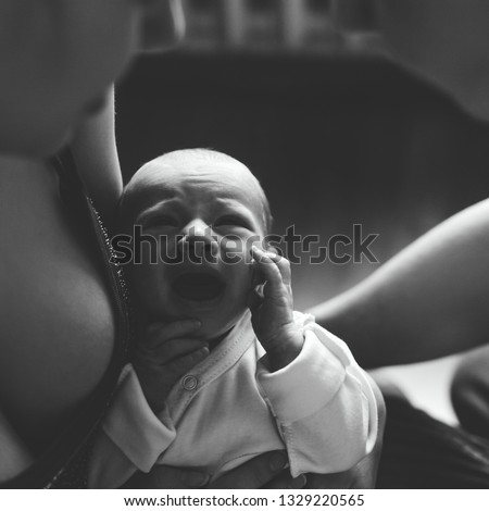 Woman and man holding on hands a newborn. Mom, dad and baby. Boy screams and cries. Happy family life. Man was born. Photo.
