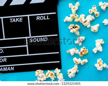 Popcorn and clapperboard on blue background. the concept of movie, film, entertainment, advertising.