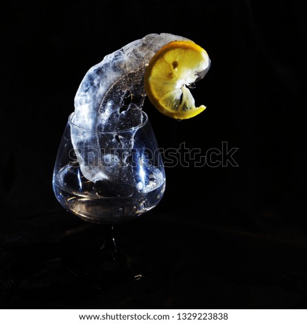 Photo of lemon and ice in yellow and black colors in wineglass which can be good illustration and beautiful abstract picture

