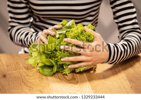 A woman in a striped shirt prepares a salad, lotus