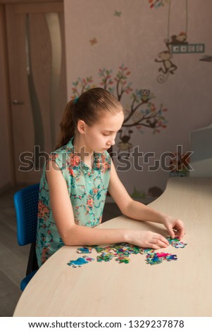 Cute little girl solving puzzle together sitting at the table