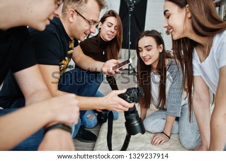 The team of photographers showing pictures on screen of camera for twins models girls on studio. Professional photographer on work.