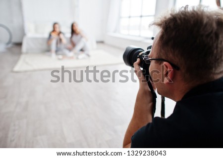 Man photographer shooting on studio two girls. Professional photographer on work.