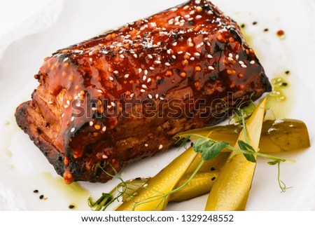 Roasted pork and vegetables on dark plate. Slow-cooked pork with sugar glazing