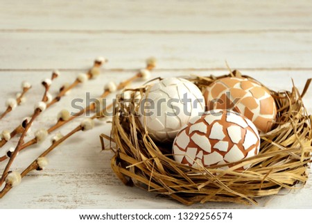 Delightful Easter decoration with eggs in the nest and willow twigs on white wooden background