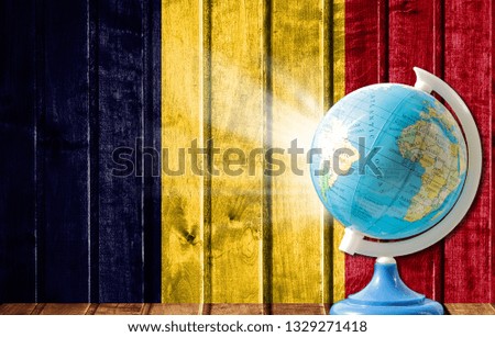 Globe with a world map on a wooden background with the image of the flag of Chad. The concept of travel and leisure abroad.