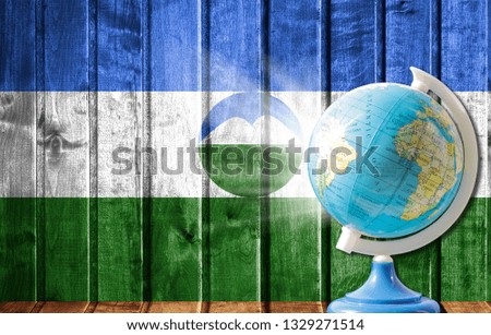Globe with a world map on a wooden background with the image of the flag of Kabardino Balkaria. The concept of travel and leisure abroad.