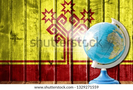 Globe with a world map on a wooden background with the image of the flag of Chuvashia. The concept of travel and leisure abroad.