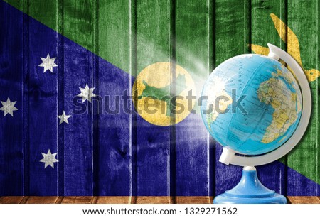 Globe with a world map on a wooden background with the image of the flag of Christmas Island. The concept of travel and leisure abroad.