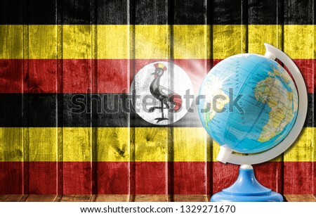 Globe with a world map on a wooden background with the image of the flag of Uganda. The concept of travel and leisure abroad.