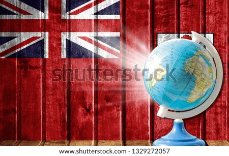 Globe with a world map on a wooden background with the image of the flag of Bermuda Islands. The concept of travel and leisure abroad.