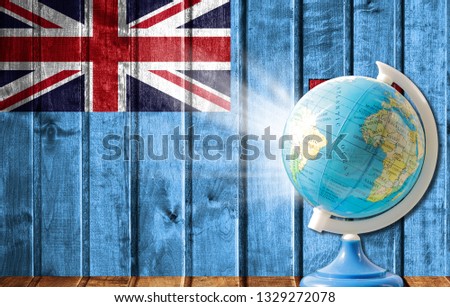 Globe with a world map on a wooden background with the image of the flag of Fiji. The concept of travel and leisure abroad.