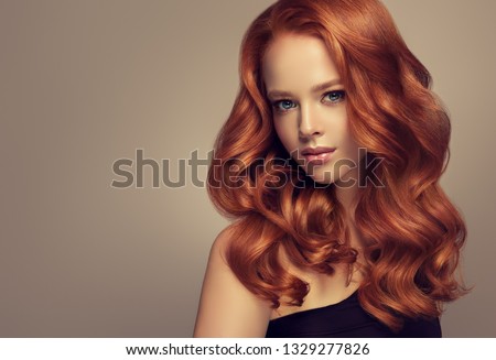 Beautiful model girl with long curly red hair . Styling hairstyle curls .Wavy and shiny swirl .