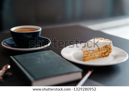 Yummy cake, cup of coffee and diary on black table
