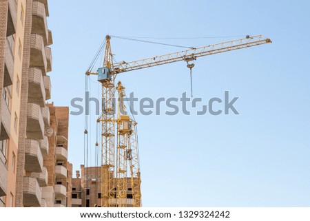 Construction crane on blue sky background. Copy space for text