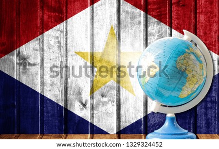 Globe with a world map on a wooden background with the image of the flag of Saba. The concept of travel and leisure abroad.