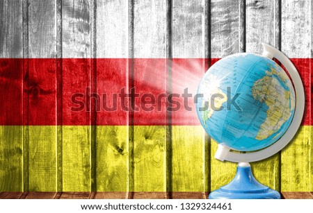 Globe with a world map on a wooden background with the image of the flag of North Ossetia. The concept of travel and leisure abroad.