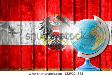 Globe with a world map on a wooden background with the image of the flag of Austria. The concept of travel and leisure abroad.
