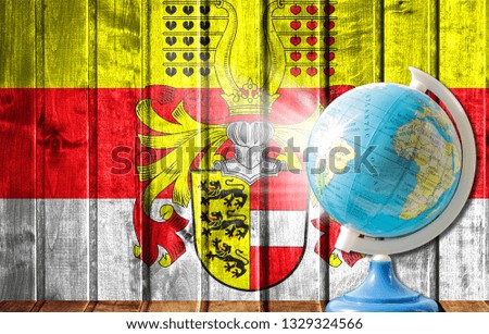 Globe with a world map on a wooden background with the image of the flag of Carinthia. The concept of travel and leisure abroad.