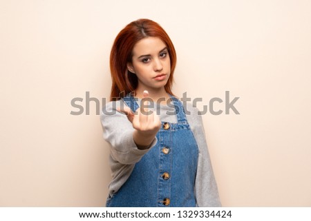 Young redhead woman over isolated background making horn gesture
