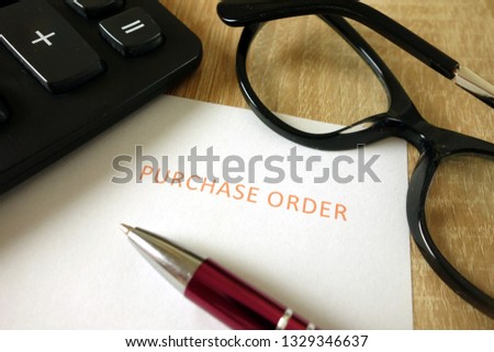 Purchase order, pen, calculator and glasses on desk