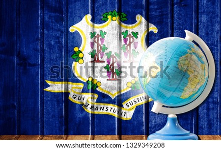 Globe with a world map on a wooden background with the image of the flag State of Connecticut. The concept of travel and leisure abroad.