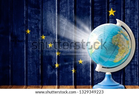 Globe with a world map on a wooden background with the image of the flag State of Alaska. The concept of travel and leisure abroad.