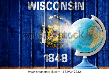 Globe with a world map on a wooden background with the image of the flag State of Wisconsin. The concept of travel and leisure abroad.