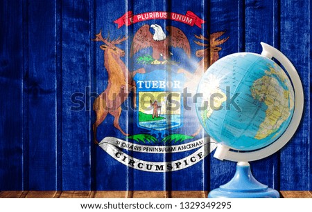 Globe with a world map on a wooden background with the image of the flag State of Michigan. The concept of travel and leisure abroad.
