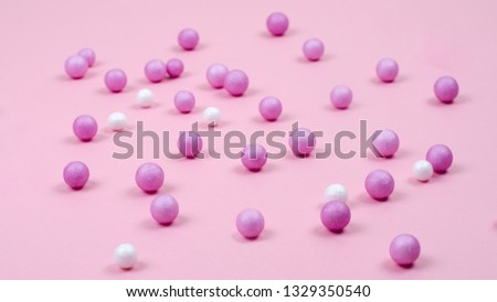 Pink and white small balls are scattered abstractly on the pink surface