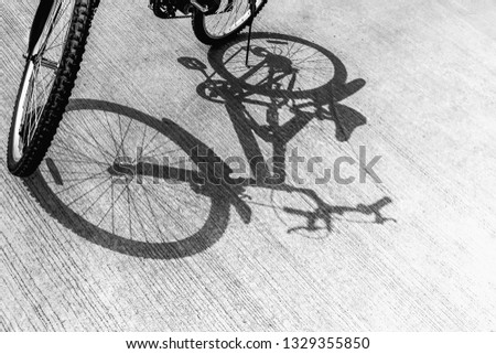 Black and white image of bicycle parked on the cement floor, with a shadow leading down, health, energy-savings and reduce pollution concept.