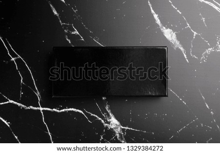 Photo of black glossy box on black marble. Template for branding identity isolated on marble background. For graphic designers presentations and portfolios marble premium luxury mock-up. 