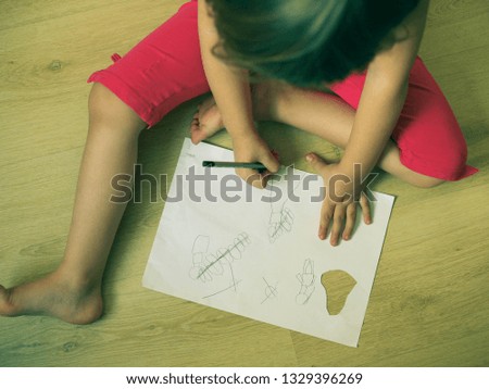 a small child draws a child's drawing on paper