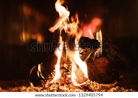 Fire in the fireplace in the lobby of a large resort in the mountains. Burning wood in the fireplace in the evening. Background of bright orange flames. Relax. Family holiday