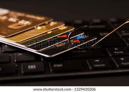 Credit card phishing attack over dark background. Computer keyboard, credit card and fish hook, close-up. Credit card fraud data leak money stealing phishing concept 