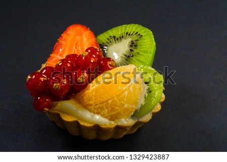 Cake with fresh bio fruit, orange, kiwi, red currant, strawberry, side view photo, black background,shade from side light, dessert, snacks pastries eco sweets