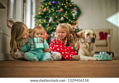 Two young girls with their baby sister and dog on Christmas day.