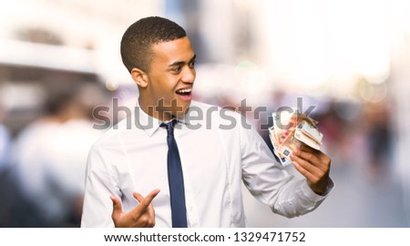 Young afro american businessman taking a lot of money in the city