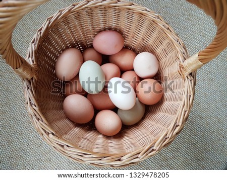 Chicken white and brown eggs in a round basket with a handle