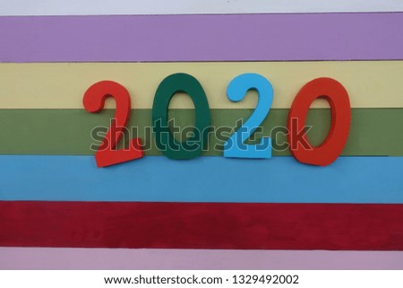 Year 2020 celebrated with multi colored wooden letters over multi colored wooden board