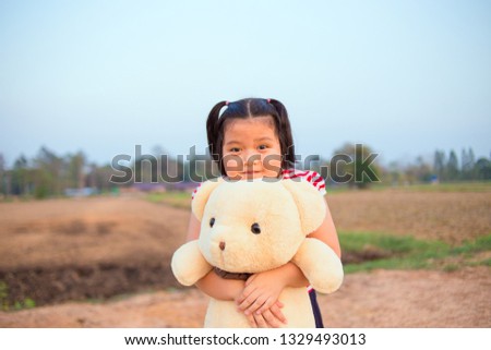 little asian Thai girl with teddy bear the enjoy hug a doll toy kids playing big bear on blue sky background.
