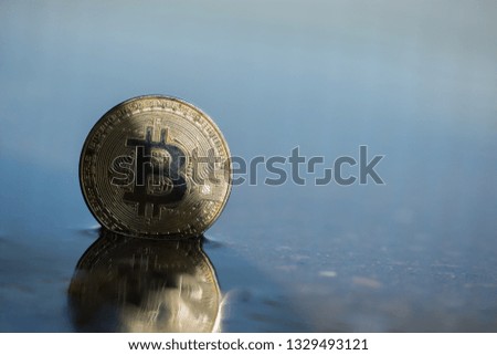 Bitcoin BTC cryptocurrency physical old coin placed on water swamp in the street with the shadow on the half of it. Macro shot. Framed on the left of the picture.