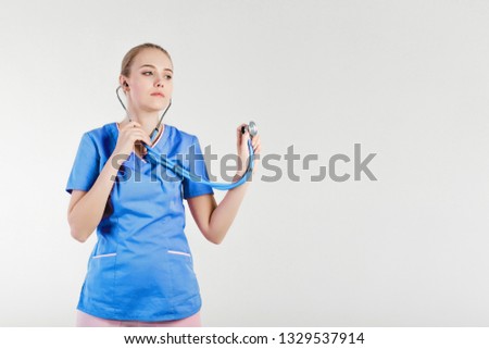 Doctor girl beautiful light gray background smiling listening  stethoscope. Concept nurse model. Positive friendly atmosphere  client patient hospital.