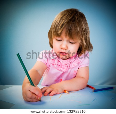 Little baby girl draws pencil on a blue background